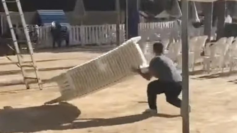 holiday resort worker unstacks chairs